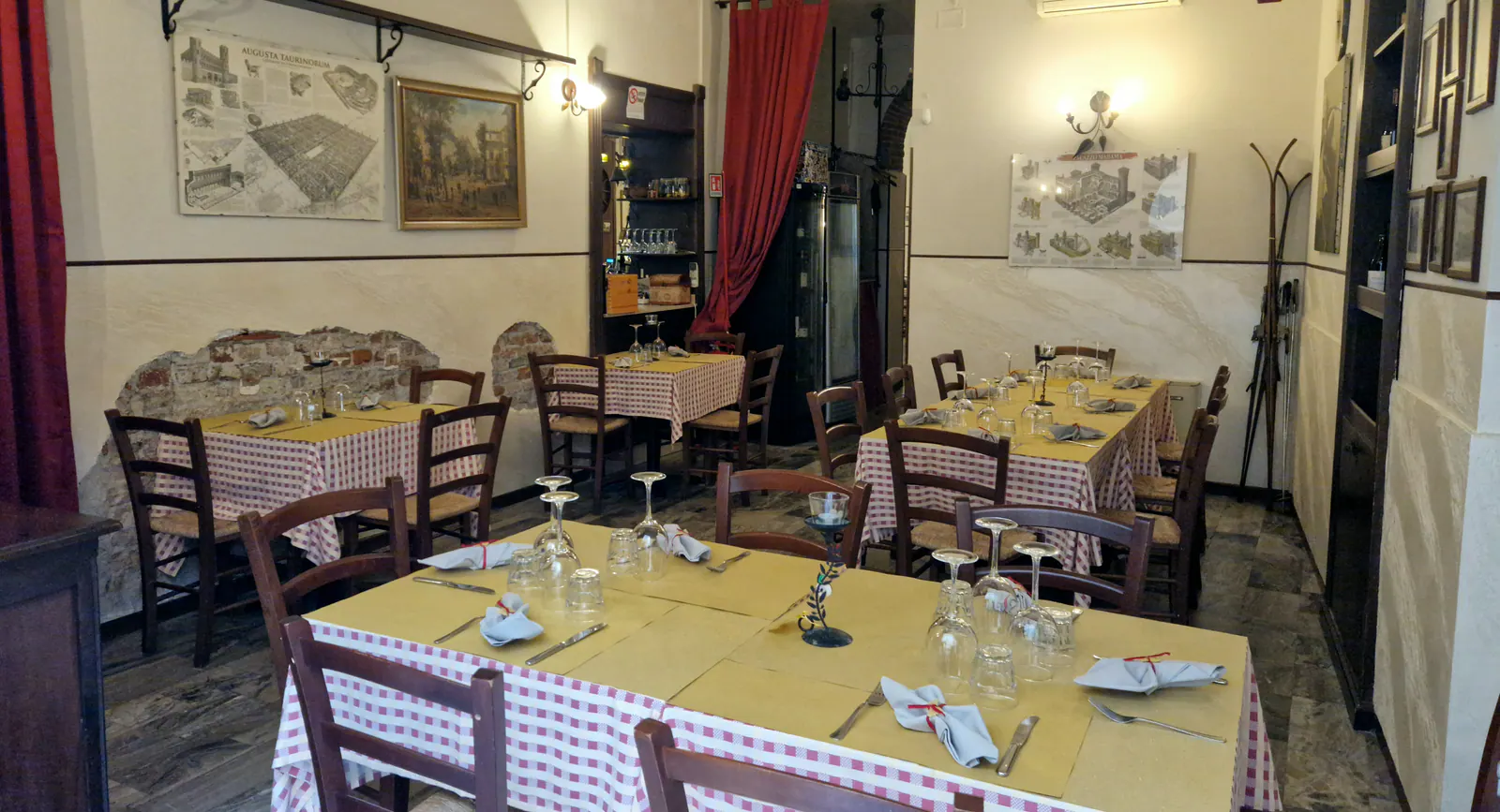 La sala di Aldente con tavoli apparecchiati, tovaglie a quadri, sedie impagliate e le tende rosse
